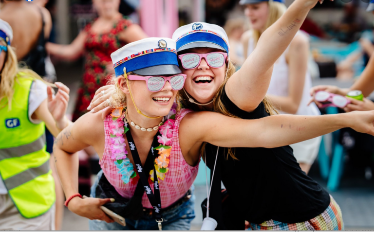 Glade studenter klar til festlig studenterkørsel i Nicedrive studentervogn, model 'Turbo Tulle, Birgitte Bacardi, Brandvarme Brian, Danse Dimsen, Ellevilde Ejgil, Iskolde Ida, Jill'icious Jill, Milli-Maria', dekoreret med bannere og danske flag, tilgængelig til en billig pris