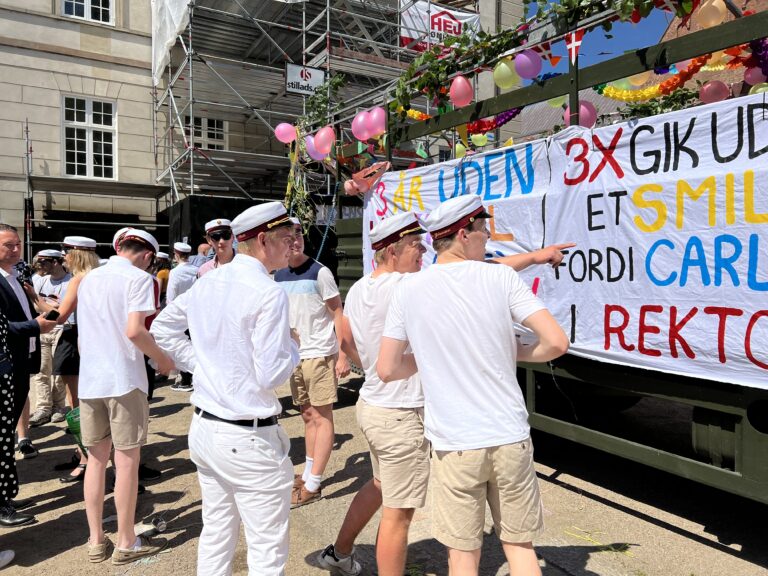 Glade studenter klar til festlig studenterkørsel i Nicedrive studentervogn, model 'Party Uartig', dekoreret med bannere og danske flag, tilgængelig til en billig pris