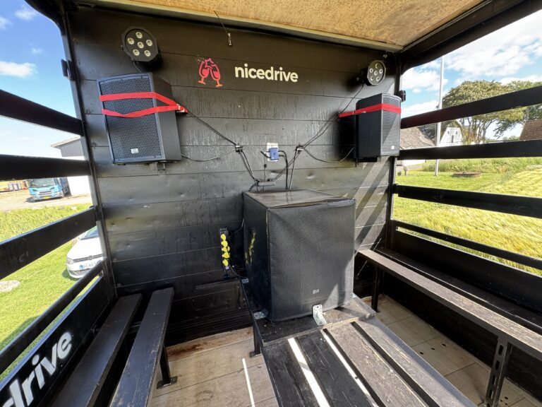 Indvendig visning af Nicedrive studentervogn, model ‘Energizer’, til studenterkørsel, siddepladser, stripperstang, kopholder, discolys og musikanlæg, tilgængelig og ledig til en billig pris