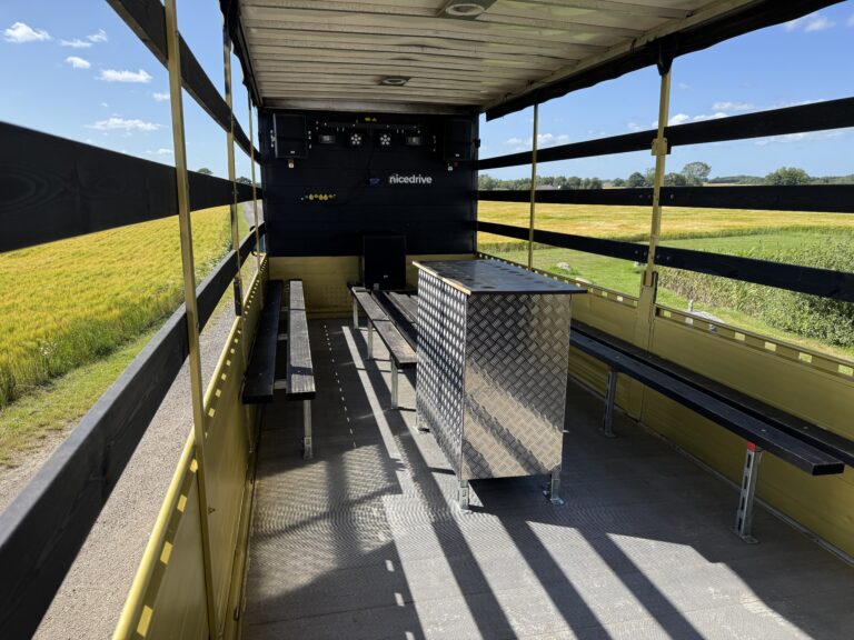 Indvendig visning af Nicedrive studentervogn, model ‘Party Promillen’, til studenterkørsel, siddepladser, bar med kopholder, discolys og musikanlæg, tilgængelig og ledig til en billig pris