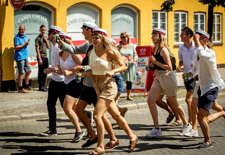 Glade studenter løber efter Nicedrive studentervogn, model ‘Beer-cardi’, med deres studenterhuer på en studenterkørsel på en solrig dag, tilgængelig til en billig pris