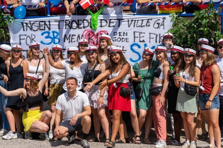 Glade studenter klar til festlig studenterkørsel i Nicedrive studentervogn, model ‘Beer-cardi’, dekoreret med bannere og danske flag, tilgængelig til en billig pris